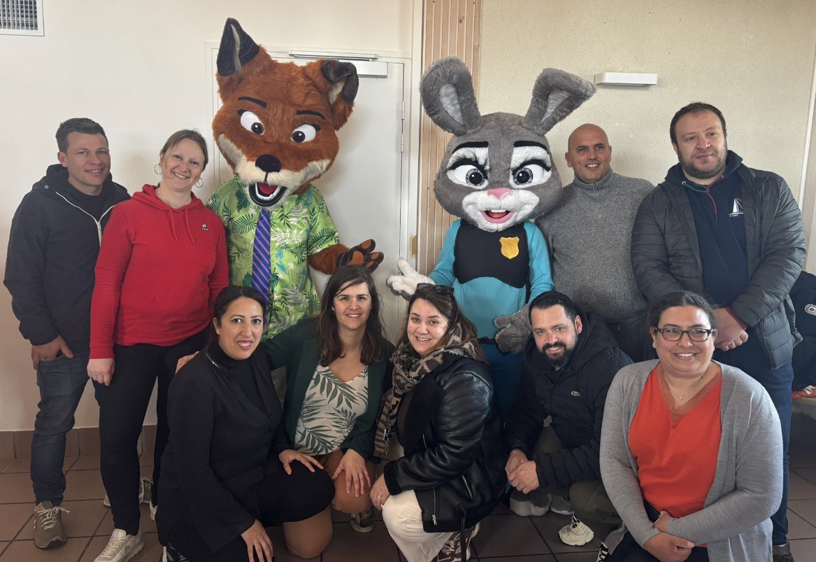 Une équipe de parents réunie avec deux mascottes lors d’un événement